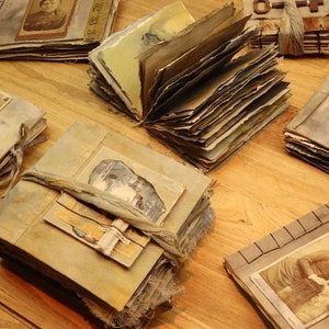 May include: A collection of vintage photo albums with worn leather covers and aged paper pages. The albums are tied with twine and feature various photographs of people and landscapes.