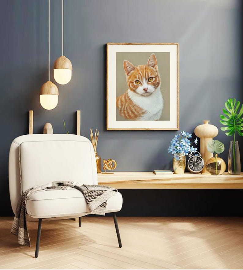 Puede incluir: Una ilustraci&oacute;n enmarcada de un gato jengibre y blanco con ojos verdes, sentado y mirando directamente a la c&aacute;mara. El marco es de madera y tiene un acabado marr&oacute;n claro. La ilustraci&oacute;n est&aacute; sobre un fondo beige.
