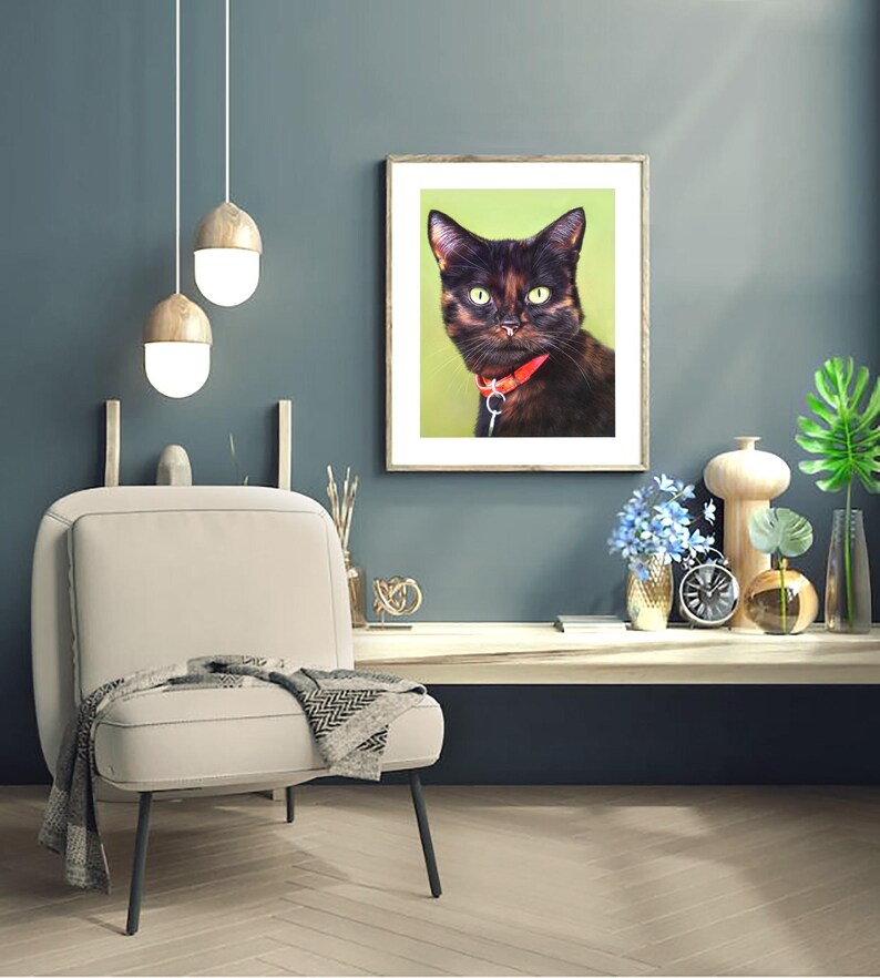 Pu&ograve; includere: Una stampa incorniciata con un gatto nero con gli occhi verdi e un collare rosso. Il gatto guarda direttamente lo spettatore. La stampa &egrave; appesa a un muro blu sopra una sedia bianca.