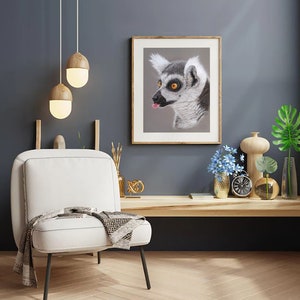 May include: A white armchair with a black throw and a wooden frame sits in a room with a grey wall. A framed print of a lemur with a long tongue hanging out is on the wall. There are two pendant lights hanging from the ceiling.
