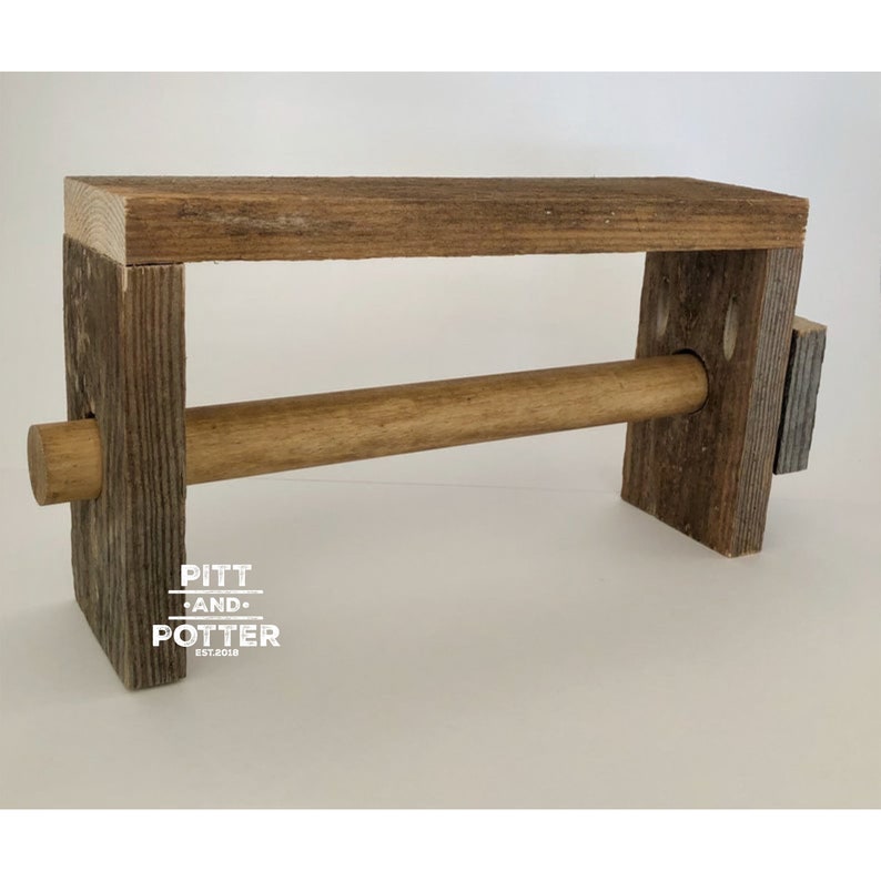 May include: Rustic wooden paper towel holder with a brown wooden dowel. The holder has a distressed wood finish and the text "PITT AND POTTER EST. 2018" is printed on the front.