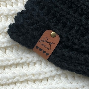 May include: Black knitted beanie with a brown leather tag that says "Jessk.ca" with a small heart design.