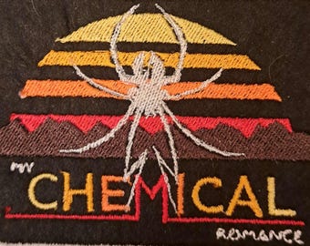 May include: Embroidered patch featuring a spider design over a sunset with the text "CHEMICAL ROMANCE". The patch has a black background with a white border. The spider is white, and the sunset colors are yellow, orange, and red.