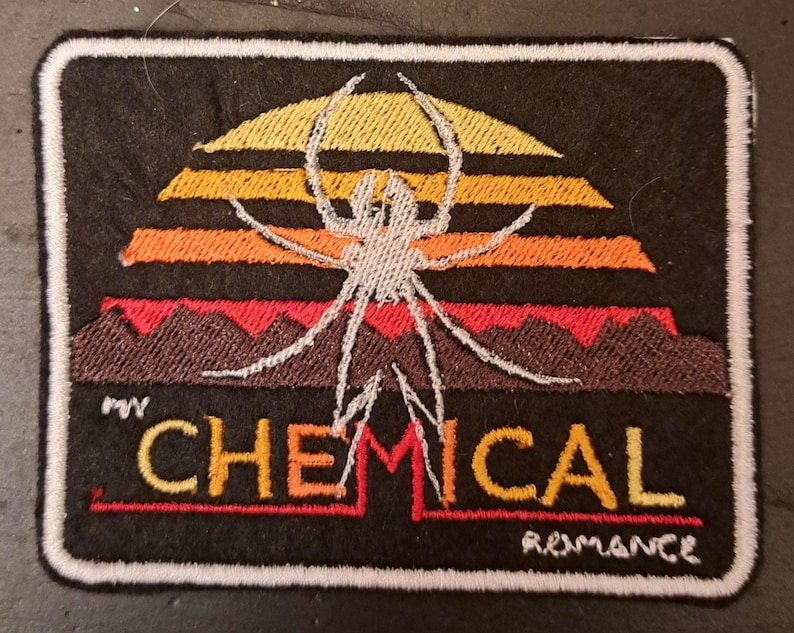 May include: Embroidered patch featuring a spider design over a sunset with the text "CHEMICAL ROMANCE". The patch has a black background with a white border. The spider is white, and the sunset colors are yellow, orange, and red.