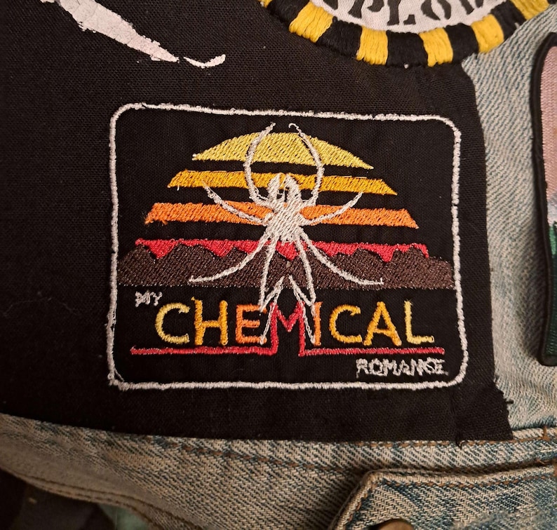 May include: Embroidered patch featuring a spider design against a sunset backdrop in yellow, orange, and red. The text "MY CHEMICAL ROMANCE" is embroidered below the design. The patch is bordered with a white stitch.