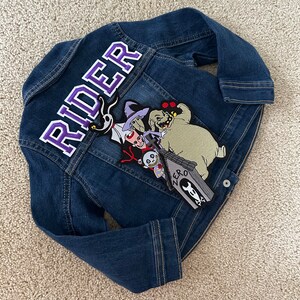 May include: A blue denim jacket with a purple "RIDER" patch on the back and a Nightmare Before Christmas character patch featuring Zero, Sally, and Oogie Boogie.