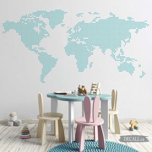 Peut inclure: Un autocollant mural représentant une carte du monde en bleu sarcelle, dans un design pixélisé. L'autocollant est affiché sur un mur blanc dans une salle de jeux pour enfants. La pièce est équipée d'une table bleu clair avec deux chaises en forme de lapin, une rose et une beige.