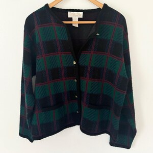 以下が含まれることがあります： ボタン留めとポケットが2つ付いた、黒、緑、赤紫の格子柄カーディガン。カーディガンには「Tallie-Ho」のラベルが付いています。
