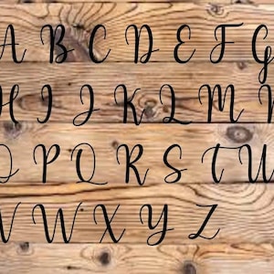 May include: A wood background with the alphabet in black cursive lettering.