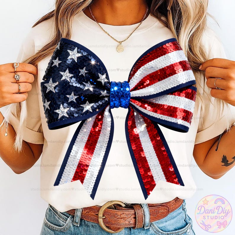 Peut inclure: Un t-shirt cr&egrave;me avec un grand n&oelig;ud orn&eacute; de sequins. Le n&oelig;ud est sur le th&egrave;me patriotique, avec une section bleue orn&eacute;e d'&eacute;toiles argent&eacute;es et une section &agrave; rayures rouges et blanches. Le n&oelig;ud est centr&eacute; sur le t-shirt.