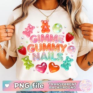 Puede incluir: Camiseta color crema con el texto "Gimme Gummy Nails" en letras de burbujas coloridas. El diseño incluye ositos de goma, corazones, fresas y burbujas. También se ven las palabras "PNG file" y "Transparent Background".