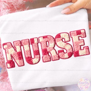 Może przedstawiać: Biała koszulka z napisem "NURSE" wyszytym w teksturowany wzór szachownicy w kolorze różowym i kremowym. Litery mają wypukły efekt, tworząc atrakcyjny wizualnie design.