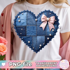 Puede incluir: Un diseño de corazón de mezclilla azul con un lazo rosa y detalles de perlas. El corazón está hecho de parches de mezclilla y tiene un borde festoneado. El diseño está en una camiseta blanca. Las palabras "PNG file" y "TRANSPARENT BACKGROUND" son visibles.