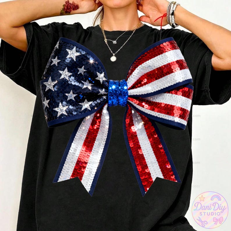 Peut inclure: Un t-shirt noir orn&eacute; d'un grand n&oelig;ud &agrave; paillettes aux couleurs du drapeau am&eacute;ricain. Le n&oelig;ud pr&eacute;sente un centre bleu, une section avec des &eacute;toiles argent&eacute;es sur fond bleu et des rayures rouges et blanches. Le t-shirt est de style d&eacute;contract&eacute;.