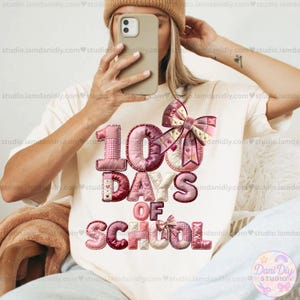 Puede incluir: Camiseta color crema con el texto "100 Days of School" en un diseño de patchwork. El diseño presenta colores rosa, rojo y crema con un gran lazo. La camiseta es de estilo casual.