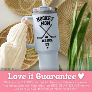 May include: A light blue stainless steel tumbler with a handle and a clear lid featuring a white straw. The tumbler displays black text reading HOCKEY MOM, JESSICA, and 09, along with a graphic of two crossed hockey sticks, a puck, and a small heart.