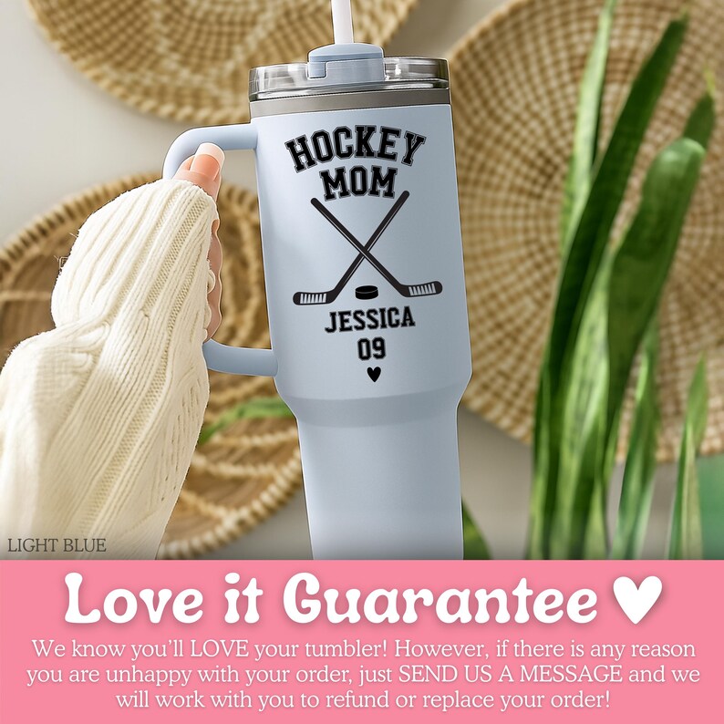 May include: A light blue stainless steel tumbler with a handle and a clear lid featuring a white straw. The tumbler displays black text reading HOCKEY MOM, JESSICA, and 09, along with a graphic of two crossed hockey sticks, a puck, and a small heart.