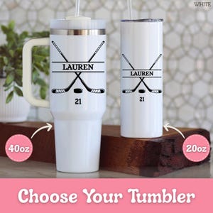 May include: White insulated tumblers with hockey graphics. One is a 1.18 litre mug with a handle, the other a 591 ml skinny tumbler. Both feature crossed hockey sticks, a puck, the name "LAUREN", and the number "21".