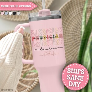 May include: A light pink tumbler with a handle and straw. The tumbler features the words "PHYSICIAN ASSOCIATE PHYSICIAN" in colorful text, along with a name and a medical symbol. The tumbler is designed for medical professionals.