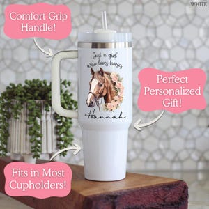 K&ouml;nnte beinhalten: Ein wei&szlig;er Becher mit Henkel, Deckel und Strohhalm. Der Becher zeigt eine Grafik eines braunen Pferdes, das von rosa Blumen umgeben ist, sowie den Text "Just a girl who loves horses" und den Namen "Hannah" in schwarzer Schreibschrift.