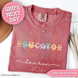 May include: Crimson-colored t-shirt with the word "EDUCATOR" repeated in a stacked design. The word "nurse" is in the center. The name "Lauren" is written in cursive. A pink circle with "SHIPS NEXT DAY" is in the upper left.