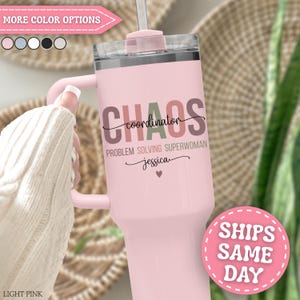 May include: A light pink insulated tumbler with a handle and a clear lid. The tumbler features the words "CHAOS coordinator PROBLEM SOLVING SUPERWOMAN Jessica" in various colors. A pink straw is inserted into the lid. The tumbler has a pink handle.