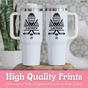 May include: Two white insulated travel mugs with black hockey graphics. Each mug displays a hockey helmet, crossed sticks, a puck, the name "LAUREN", and the number "21". The mugs have white handles and lids. The text "High Quality Prints" is also visible.
