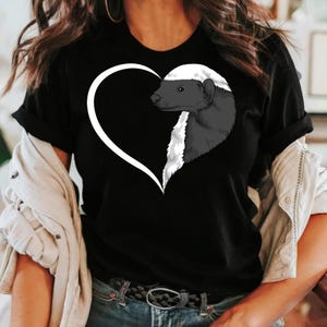 May include: Black t-shirt featuring a white heart shape with a badger illustration inside. The badger is depicted in shades of gray and white, with a black head and a white stripe. The shirt is a casual wear item.