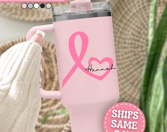 Può includere: Un bicchiere in acciaio inossidabile rosa chiaro con manico, coperchio trasparente e cannuccia. La parte anteriore presenta un nastro di sensibilizzazione rosa brillante integrato con un cuore e il nome Hannah in corsivo nero.