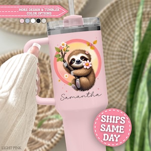 May include: A light pink tumbler with a handle and a clear lid featuring a graphic of a brown sloth hanging from a branch with white and pink flowers inside a circular frame. The name Samantha is printed in black script below the sloth illustration.