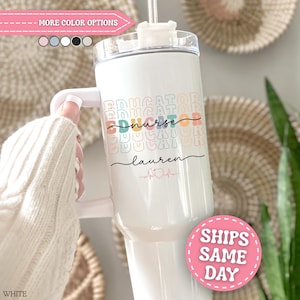 May include: A white stainless steel tumbler with a handle and a clear lid. The front features the word EDUCATOR repeated in pastel colors, the word nurse in black script, the name lauren in black script, and a pink heart with an EKG line.