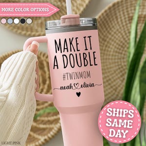 May include: A light pink tumbler with a handle and a straw. The tumbler has the text "MAKE IT A DOUBLE #TWINMOM noah & olivia" in black. The tumbler is shown with a light pink handle and a white straw. The tumbler is a great gift for a twin mom.