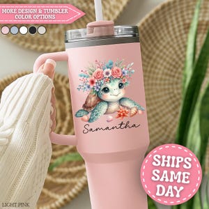 May include: A light pink tumbler with a handle, featuring a cartoon turtle wearing a floral crown. The turtle is surrounded by coral and the name "Samantha" is written below. The tumbler has a straw and a lid. The text "MORE DESIGN & TUMBLER COLOR OPTIONS" is visible.