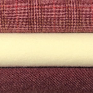May include: Three fabric swatches stacked on top of each other. The top swatch is a pink and brown plaid, the middle swatch is a cream color, and the bottom swatch is a deep burgundy.