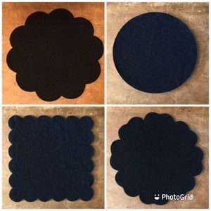 May include: Four black felt coasters with scalloped edges. The coasters are arranged in a grid pattern on a wooden surface.