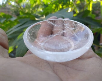 May include: A clear crystal bowl with a smooth, polished surface. The bowl is slightly curved and has a reflective quality.