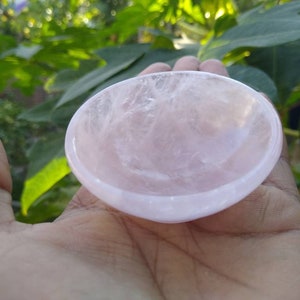 May include: A small, pink, rose quartz bowl. The bowl is smooth and polished, with a slightly rounded shape.