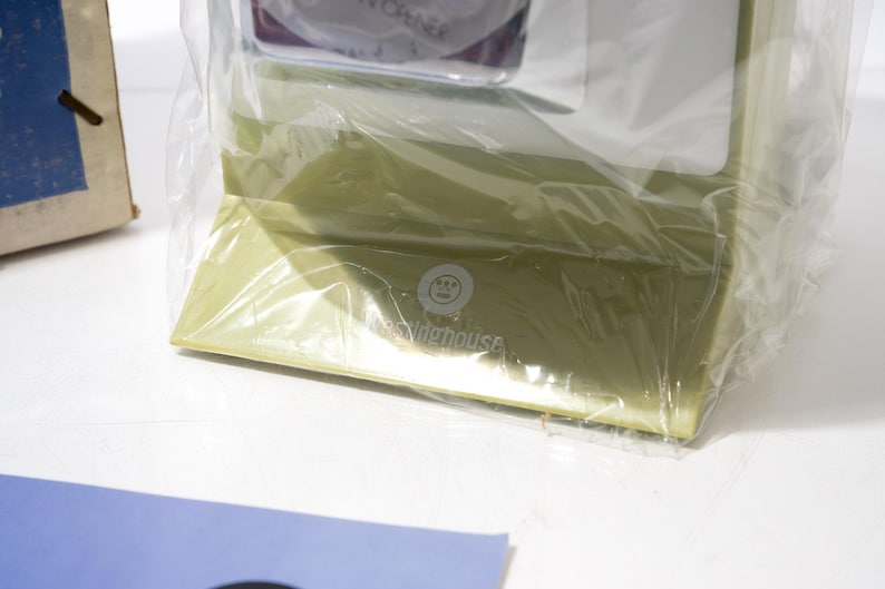 May include: A light green box wrapped in clear plastic. The box has the text "The Widehouse" printed on it. A blue and white card is in the foreground.