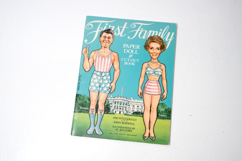 May include: A vintage "First Family" paper doll and cut-out book featuring illustrations of Ronald and Nancy Reagan. The cover is turquoise with the title in white script and illustrations of the couple in swimwear.