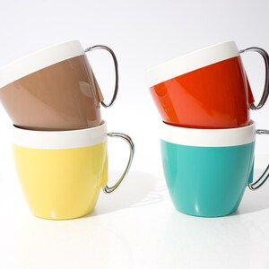 Puede incluir: Una taza de cerámica blanca con un asa negra y el texto "But First, Coffee" en negro, en negrita. La taza está sobre una superficie blanca.
