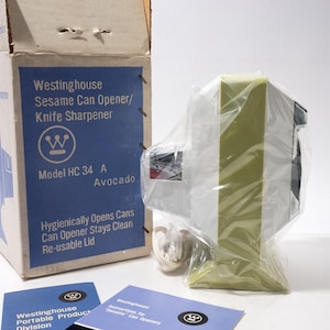 May include: A vintage Westinghouse Sesame Can Opener/Knife Sharpener, model HC 34 A, in its original box. The box is blue and white, with product information and the word "Avocado" printed on it. The can opener is avocado green and white, wrapped in plastic.