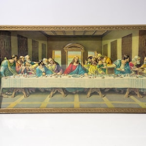 May include: A framed, three-dimensional artwork depicting the Last Supper. The scene features Jesus and his disciples seated at a long table, with detailed figures and a warm color palette. The frame is a gold color.
