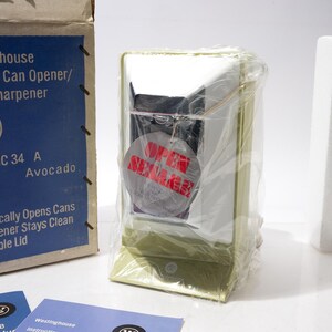 May include: A vintage Westinghouse Sesame Can Opener/Knife Sharpener, model HC 34 A, in its original box. The box is blue and white with product information. The can opener is avocado-colored and wrapped in plastic. A tag reads "OPEN SUMMER".