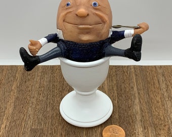 Humpty Dumpty en miniatura hecho a mano sentado en un huevera