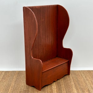 Può includere: Una panca di legno con schienale alto e seduta. La panca è dipinta di un colore rosso scuro.