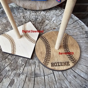 May include: Two wooden baseball-themed display stands. One is a home plate shape, the other is round. Both have a light brown finish with engraved baseball stitching and a wooden dowel. The round stand has the name "ROZENE" engraved. The home plate stand has the text "Digital Download".