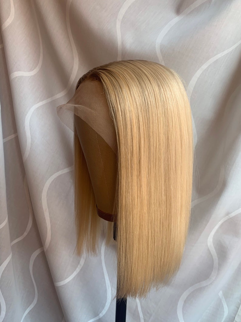 May include: A blonde human hair wig with a straight style and a lace front. The wig is on a mannequin head.