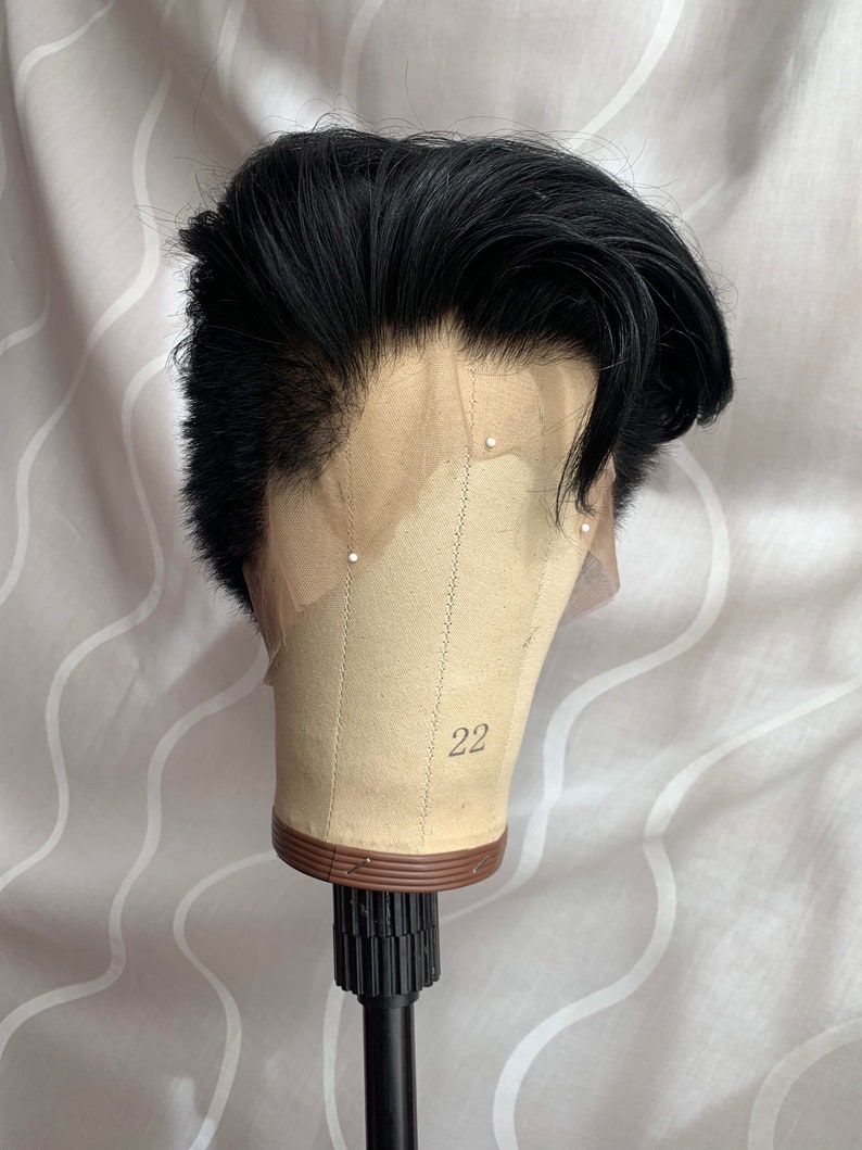 May include: Black men's wig with a short, styled haircut. The wig is on a mannequin head with a brown base and the number 22 printed on it.