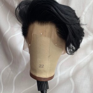 May include: Black wig on a mannequin head with a number 22 on the front. The wig has a short, layered style.