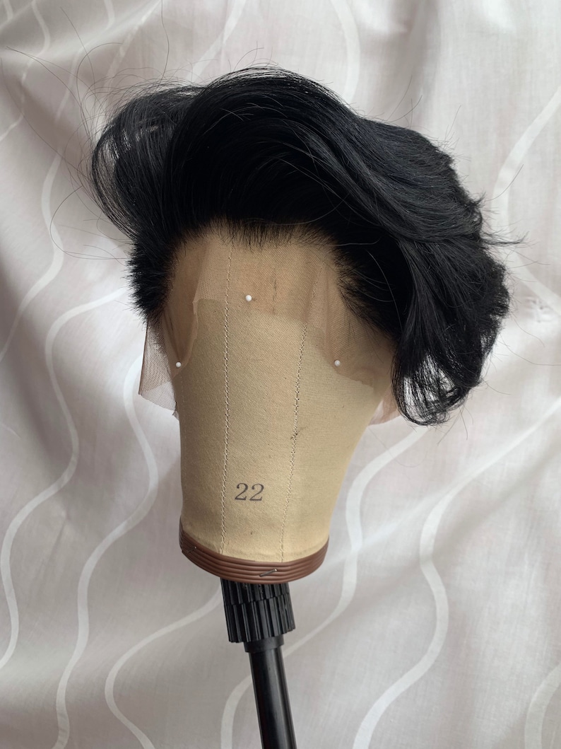 May include: Black wig on a mannequin head with a number 22 on the front. The wig has a short, layered style.